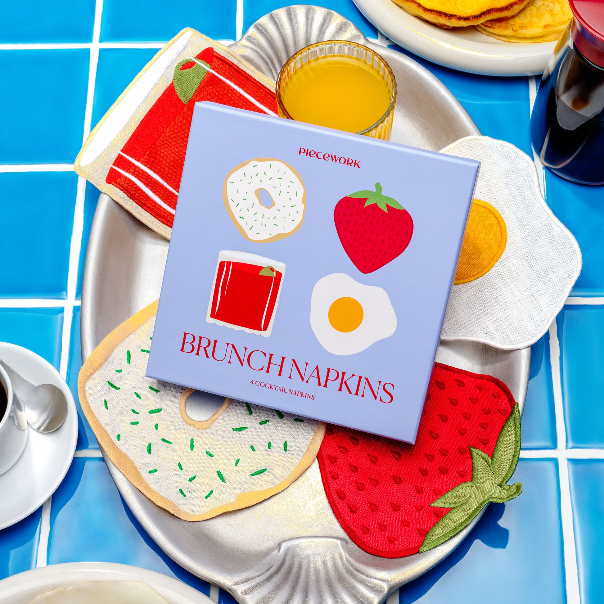 Piecework Brunch Napkins boxed gift set styled with juice, pancakes, and 100% linen napkins shaped like brunch favorites.