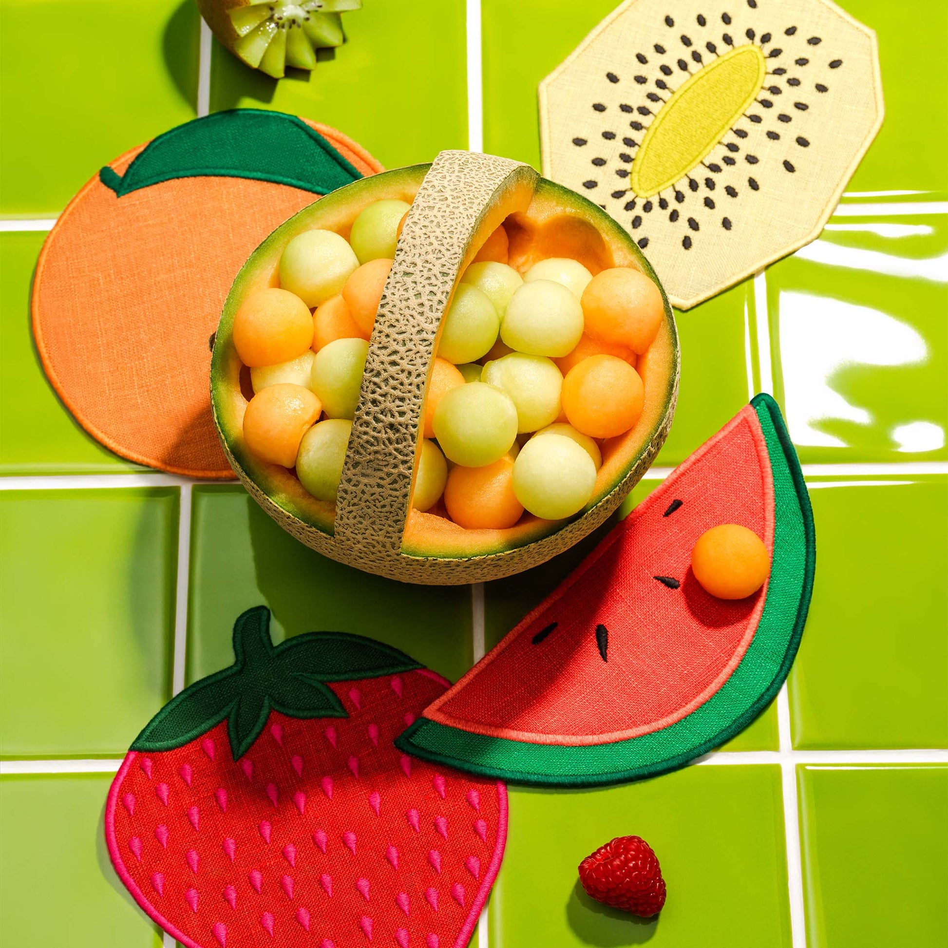 Fruit-shaped cocktail napkins by Piecework including a strawberry, orange, kiwi, and slice of watermelon—styled with melon balls for colorful entertaining.