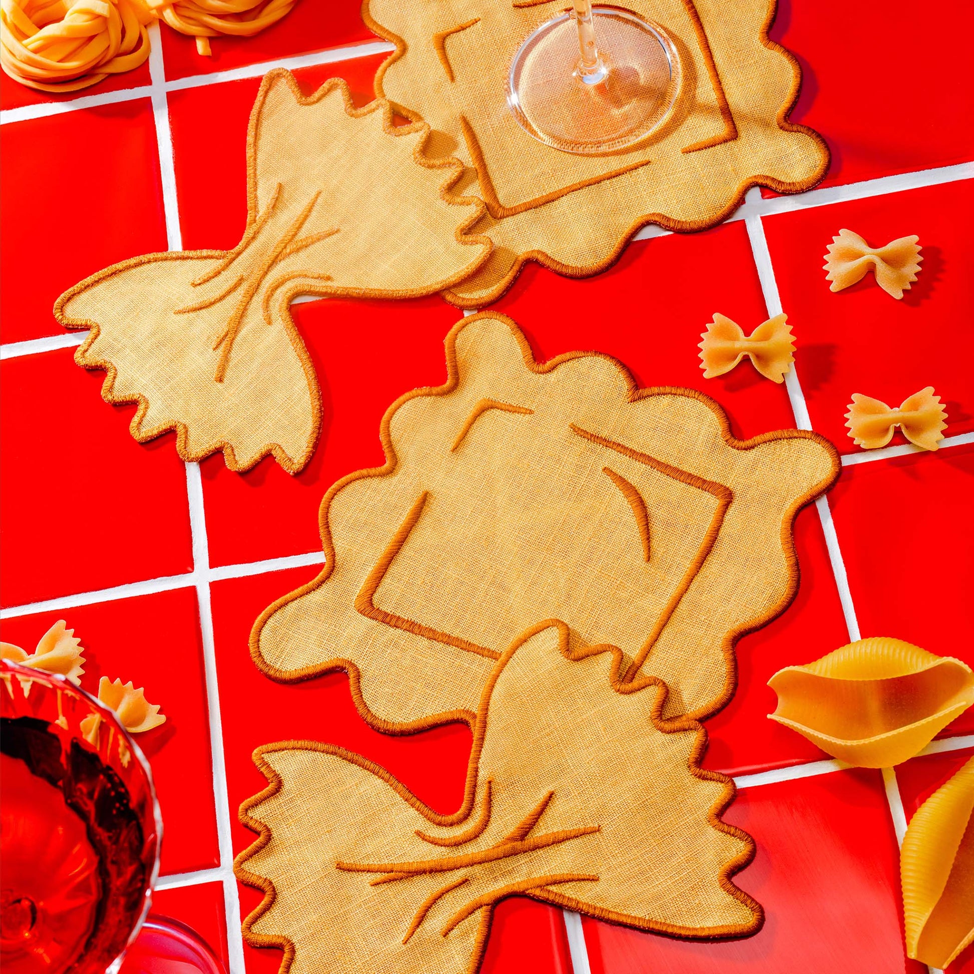 Ravioli and farfalle-shaped cocktail napkins by Piecework styled with pasta and red wine—perfect for gifting or dinner party hosting.
