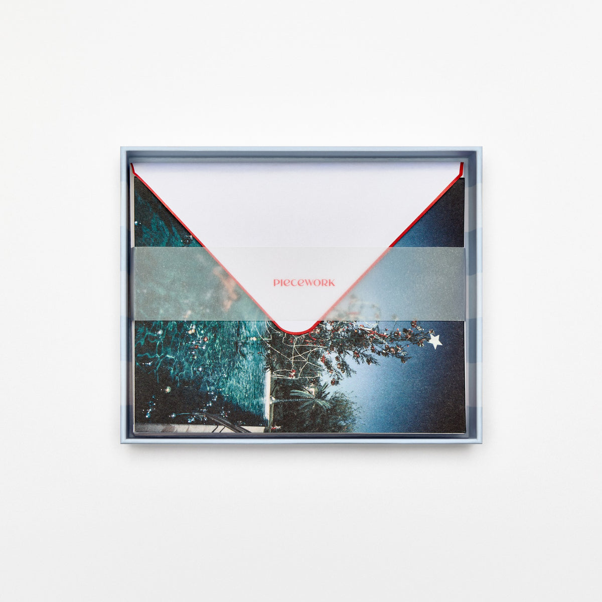 Piecework Christmas Swim Stationery Set: open blue-striped box of poolside tree notecards and envelopes under a vellum band