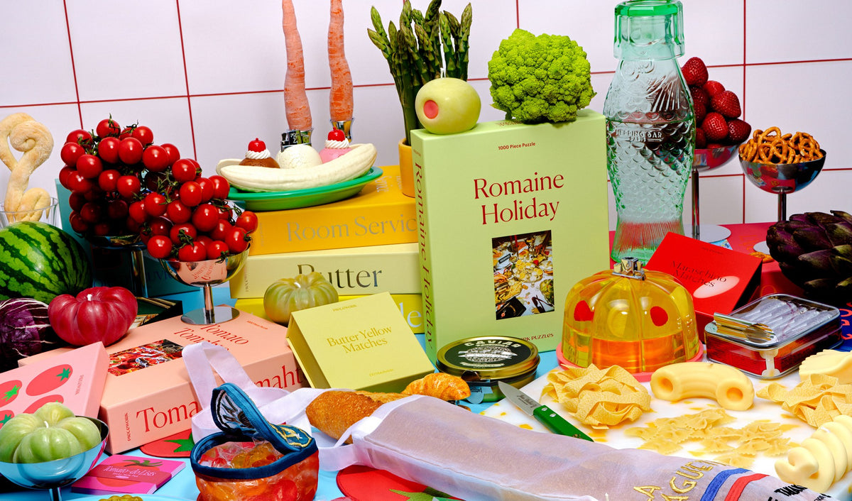 Piecework Romaine Holiday, Butter, and Tomato Tomahto puzzles with Butter Yellow Matches, styled among fresh produce, pasta, and bread