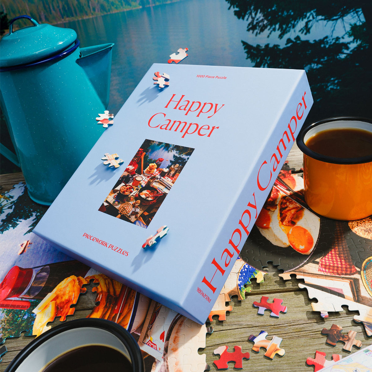 Happy Camper puzzle box with puzzle pieces and coffee cups on a table