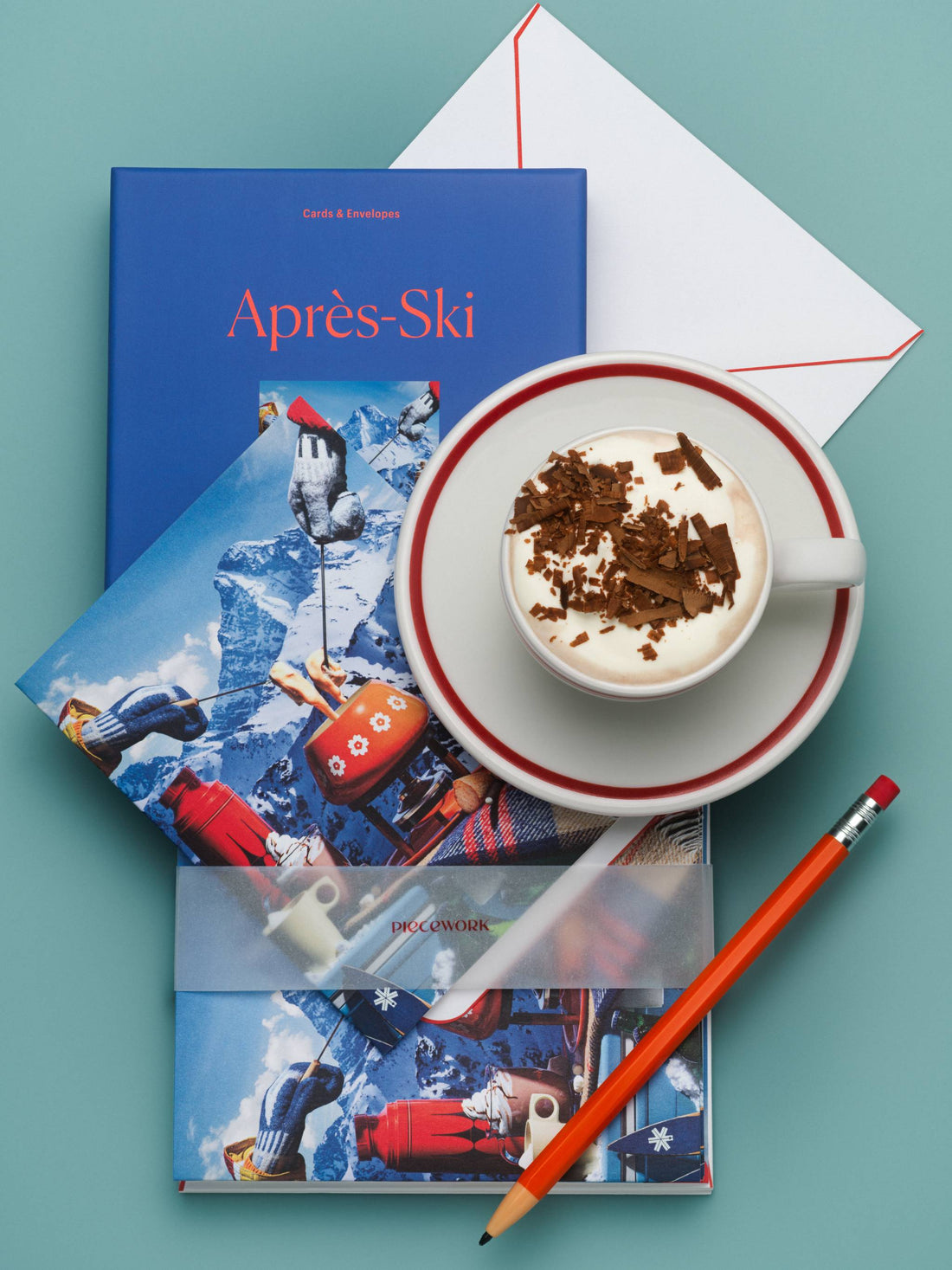 Piecework Après-Ski boxed notecard set with a skier photo card, cup of hot chocolate and red pencil on teal