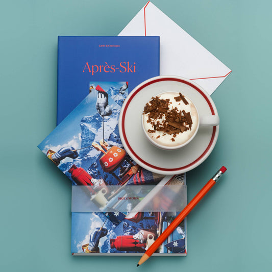 Piecework Après Ski Stationery Set: cobalt box, notecards and envelope on teal with a cup of hot cocoa and an orange pencil