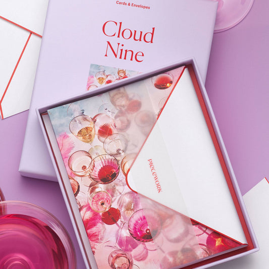 Piecework Cloud Nine Stationery Set: lavender box and open tray of glassware notecards and envelope among rosé glasses