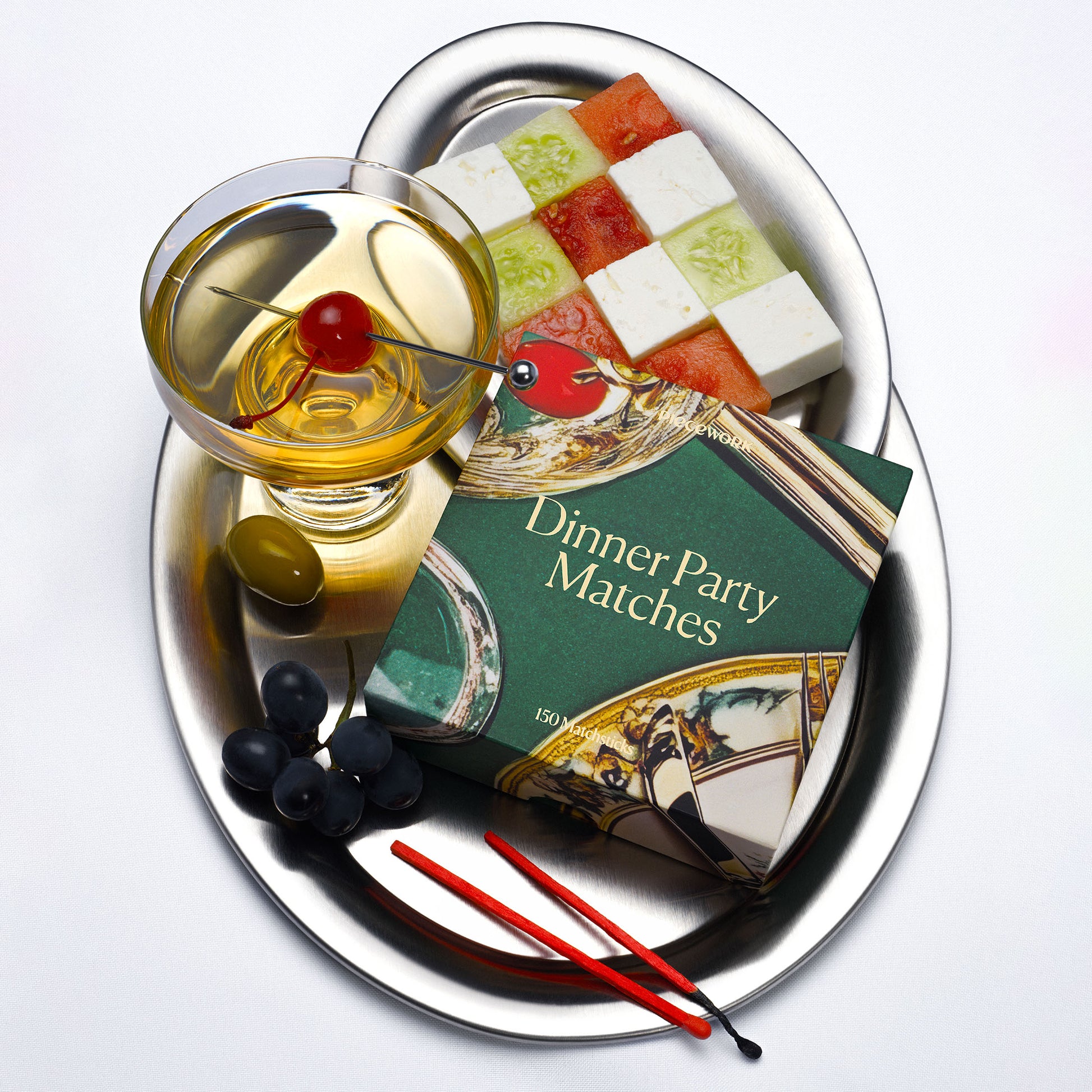 Statement red Dinner Party matches, shown with a cocktail, and cheeseboard on a silver tray.