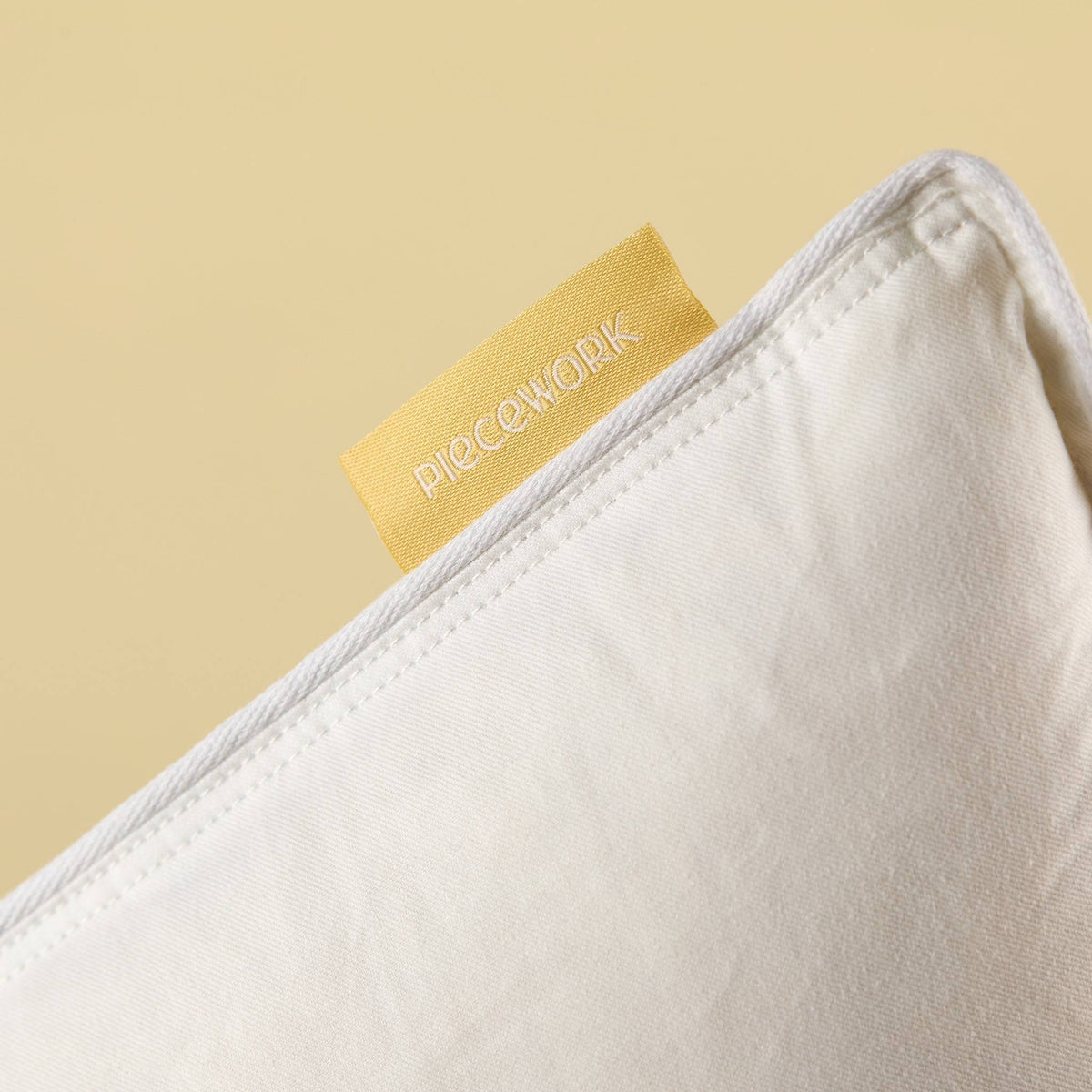 Feather Pillow Insert corner with white cotton shell and Piecework label