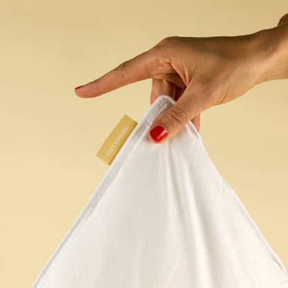 Hand holding the corner of a white Feather Pillow Insert