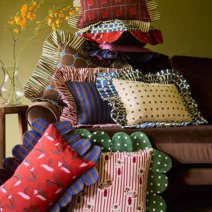 Jewel Stripe Ruffle Pillow in a stack of Piecework pillows on a velvet sofa