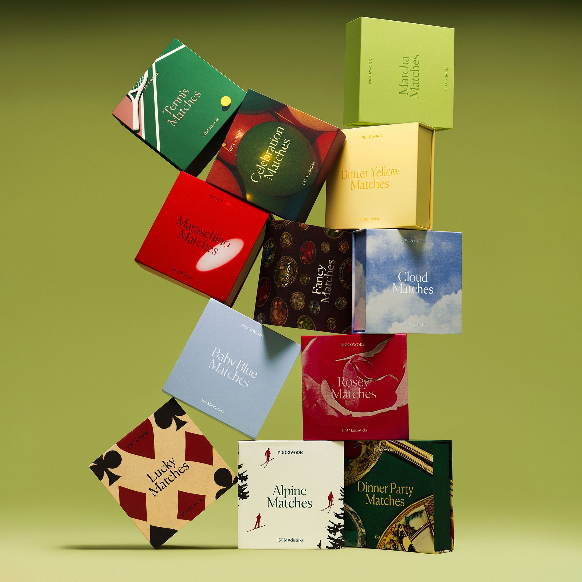 Piecework Matches Collection: A lineup of statement-making matchboxes arranged in a tower on a green background.