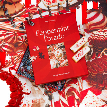 Peppermint Parade puzzle box resting on the finished red-and-white candy puzzle, with toy soldiers and frosted cookies