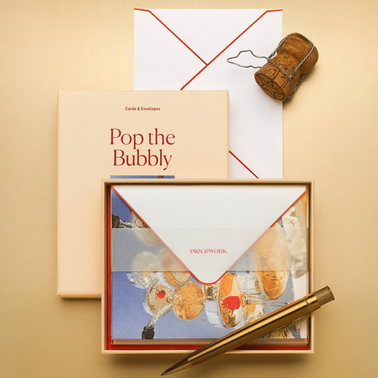 Piecework Pop the Bubbly Stationery Set: peach box and open tray of notecards under a vellum band with a champagne cork