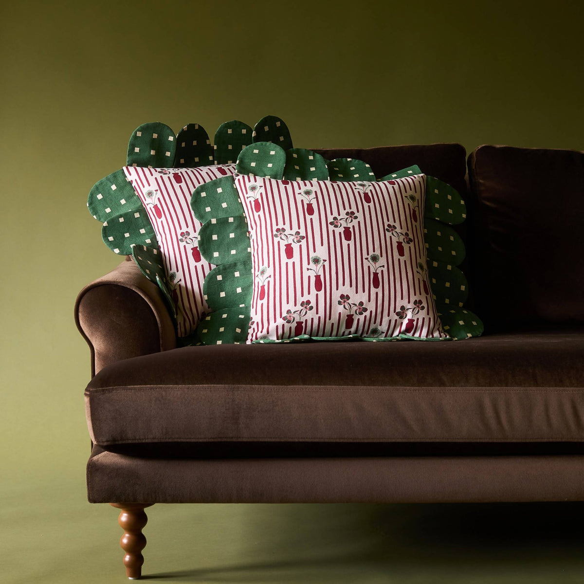 Two Posie Check Petal Pillows on a brown velvet sofa