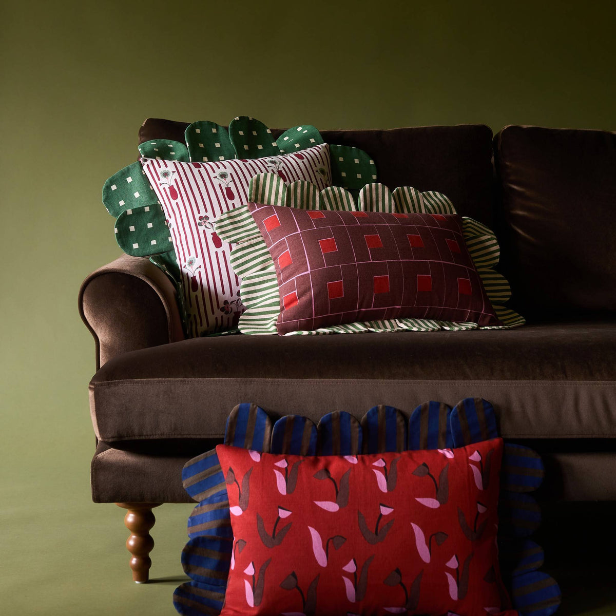 Posie Check Petal Pillow with other Piecework pillows on a velvet sofa