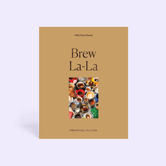 A 1000-piece puzzle titled 'Brew La-La' by Piecework, featuring a tan cover with a colorful central graphic of various coffee cups, set against a light lavender background.