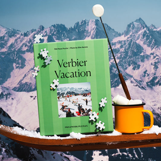 Green striped puzzle box titled 'Verbier Vacation' with a yellow mug and marshmallows against a snow-topped mountain background.