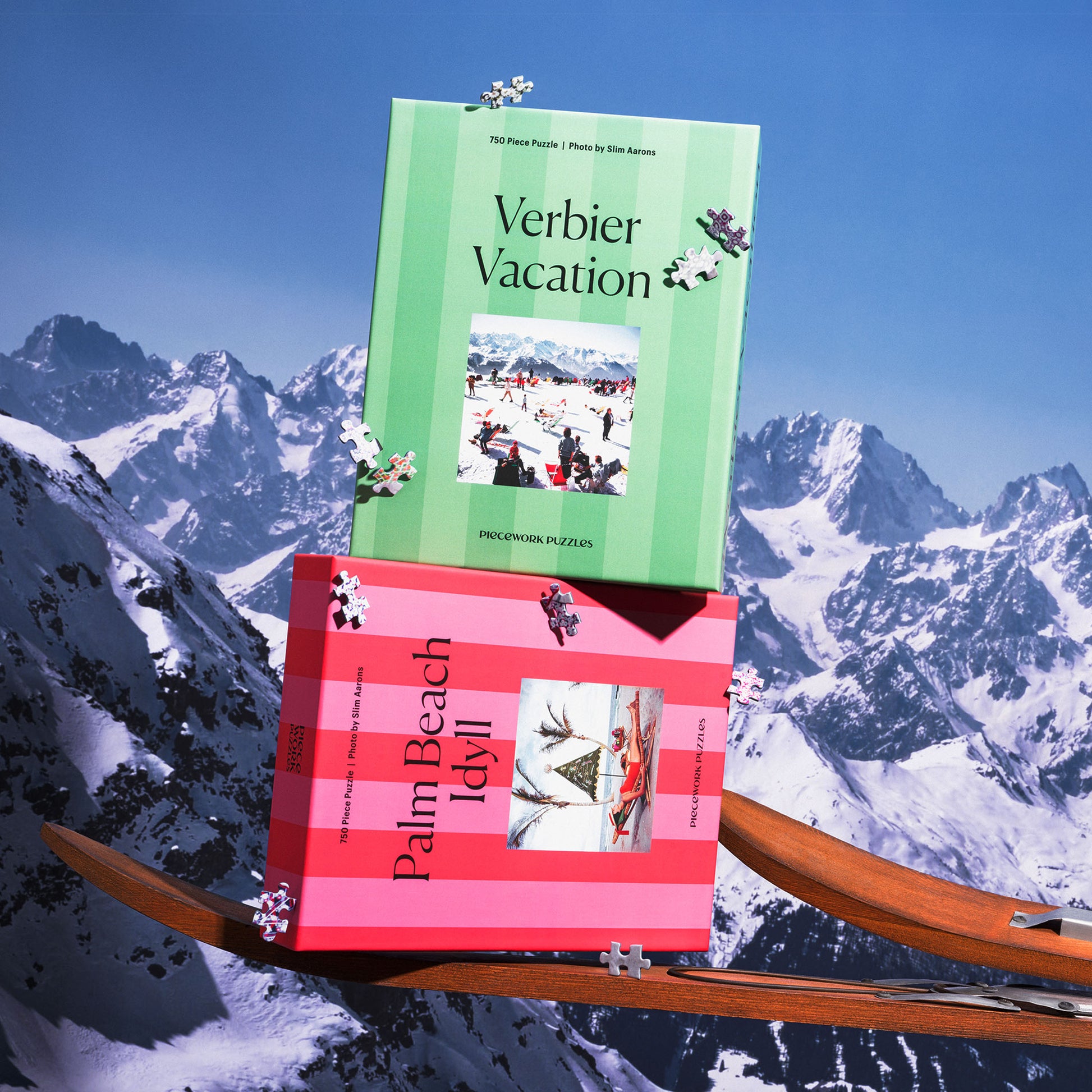 Two puzzle boxes titled 'Verbier Vacation' and 'Palm Beach Idyll' on vintage wooden skis with a snow-topped mountain background.
