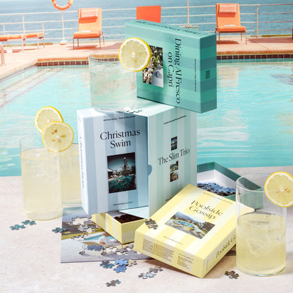 Slim Aarons Trio Set puzzle boxes arranged poolside next to lemonade and loose puzzle pieces