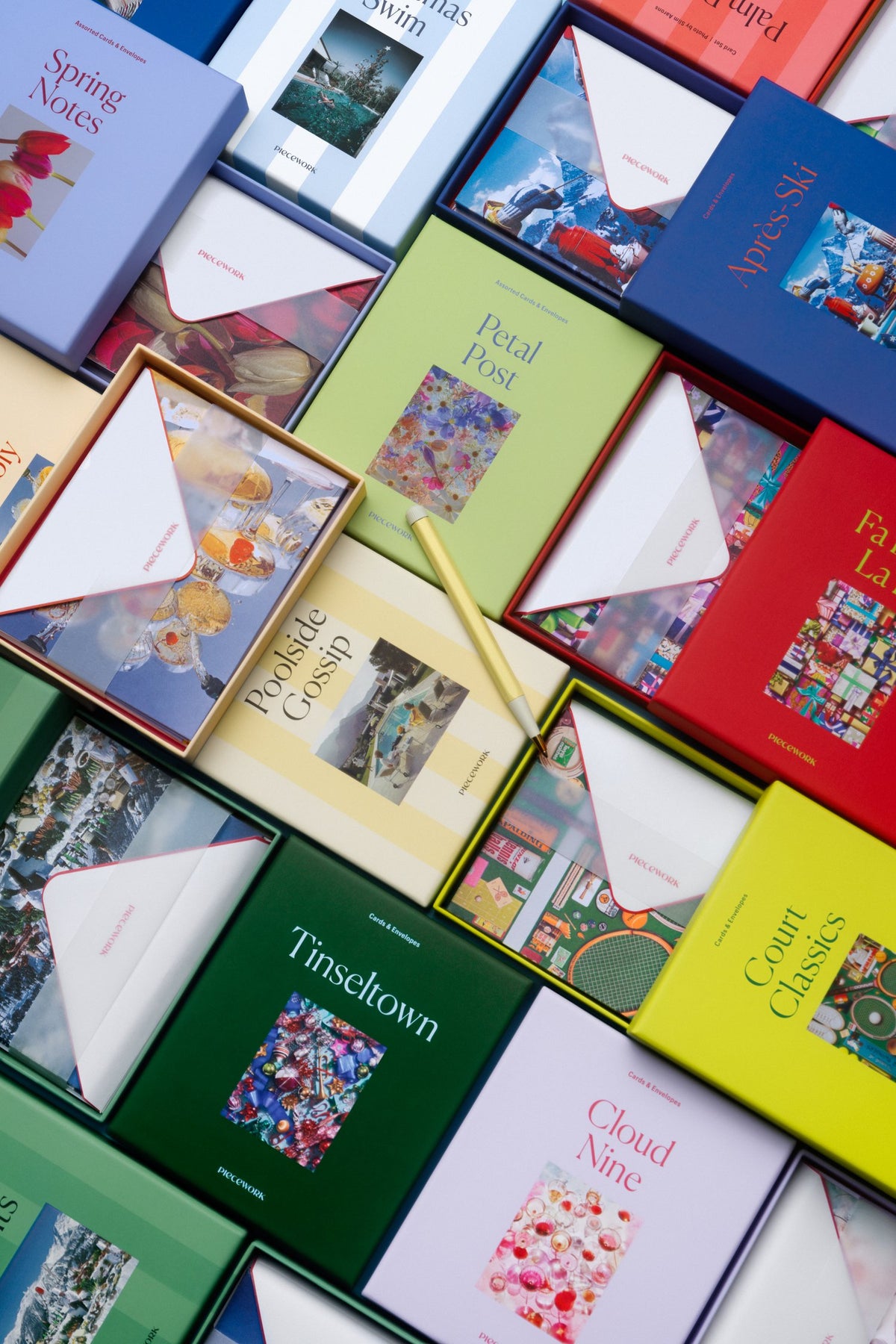Overhead spread of colorful Piecework stationery card sets, including Tinseltown, Cloud Nine, Petal Post, and Court Classics, with open envelopes
