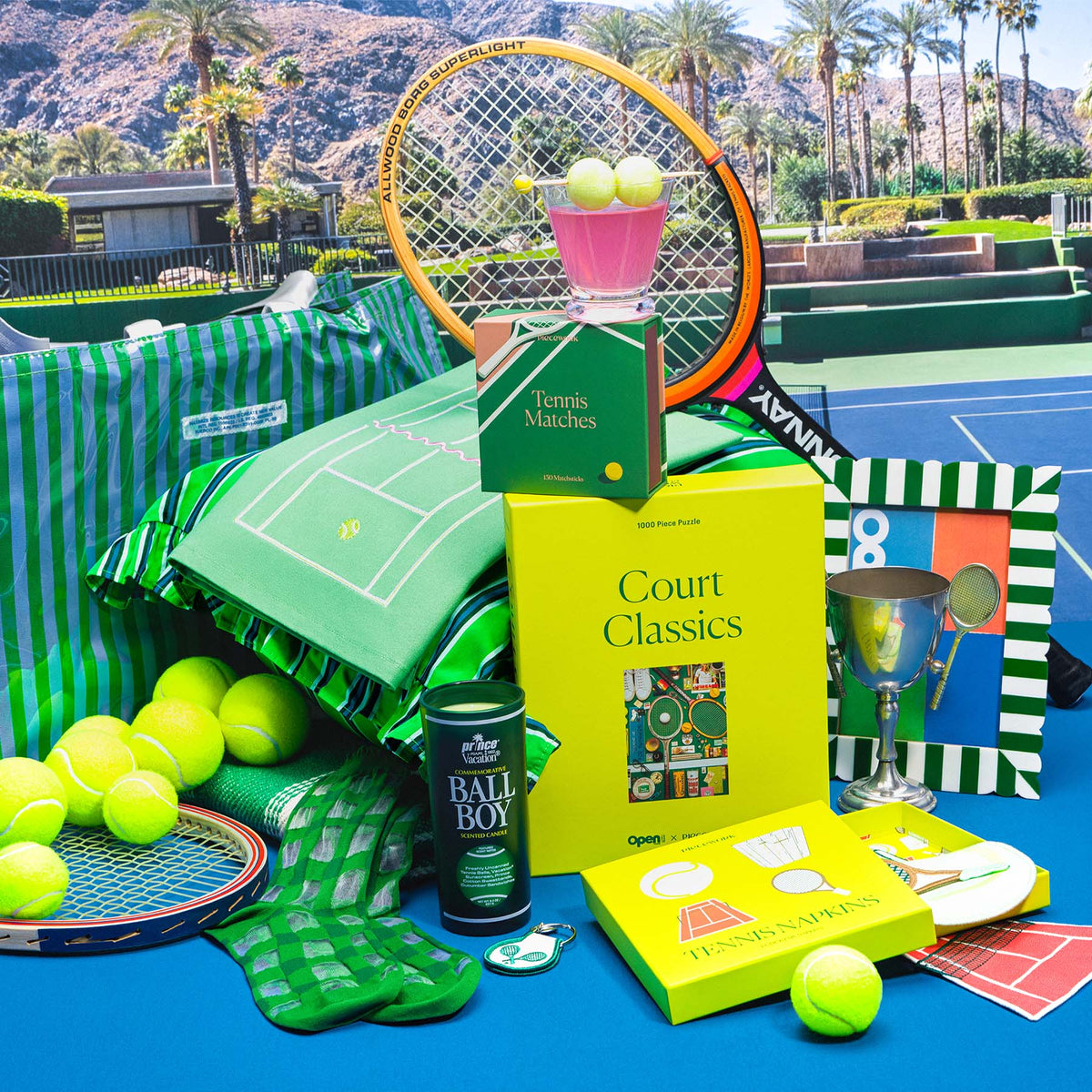 Tennis-themed gifts including tennis matches and a tennis puzzle on a tennis court with palm trees in the background.