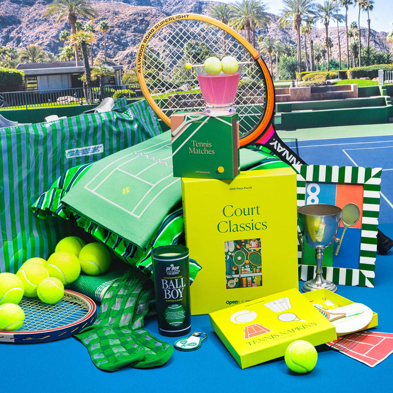 Tennis-themed gifts including tennis matches and a tennis puzzle on a tennis court with palm trees in the background.