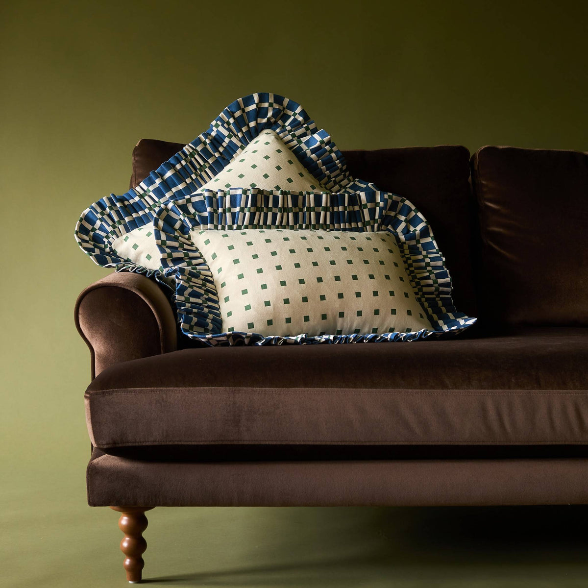 Two Tiny Checks Ruffle Pillows on a brown velvet sofa