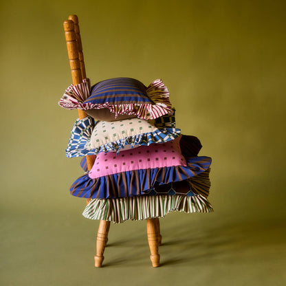 Tiny Checks Ruffle Pillow stacked with Piecework pillows on a wooden chair