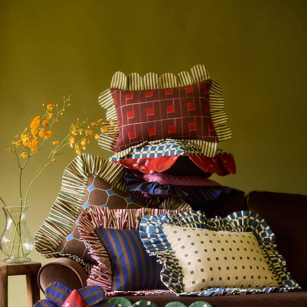 Venetian Check Petal Pillow in a stack of Piecework pillows on a velvet sofa