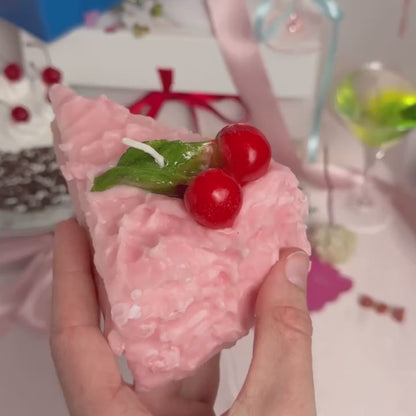 A Cherry Cake Slice Candle being shown in a person's hand and set down on a surface.